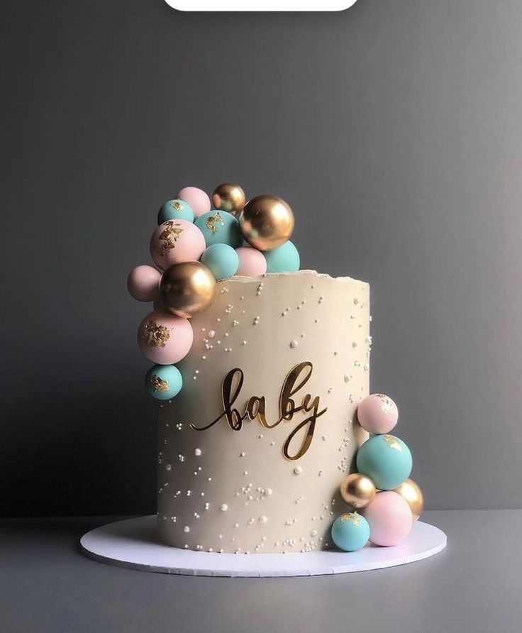 a baby shower cake with gold, blue and pink baubles on it's side