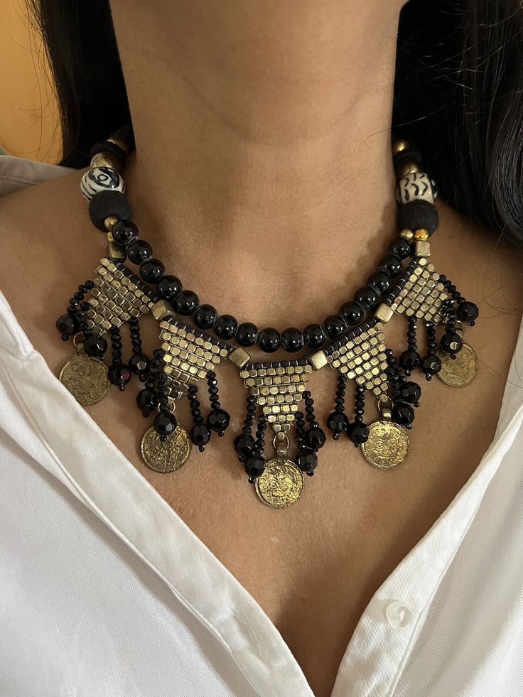 Complement your personality with this boho-chic trendy unique design.  The gorgeous antique collar necklace is beautifully crafted by our local Indian artisans in tribal coins and gold, black and hand painted beads. Styling Tip: Wear them with a white shirt and denim jeans. Length of necklace when falls on the body: approximately 8 inches.  Comes with a Dori and is adjustable. Weight of Necklace: 80 grams Black Bohemian Choker, Bohemian Jewelry With Black Beads, Round Shape, Bohemian Jewelry With Black Round Beads, Bohemian Jewelry With Black Beads, Handmade Black Brass Necklace, Traditional Adjustable Boho Collar Necklace, Bohemian Black Beaded Jewelry, Festive Handmade Black Necklace, Black Metal Necklace For Festive Occasions