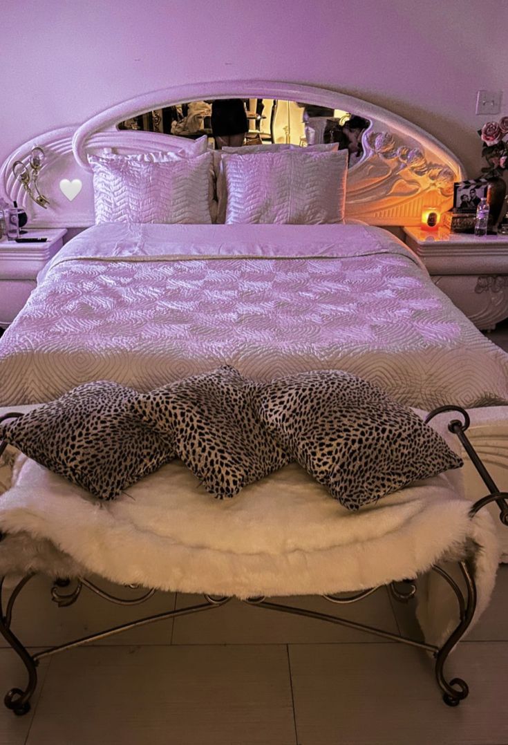 a leopard print bed spread and pillows on a metal frame with a mirror in the background