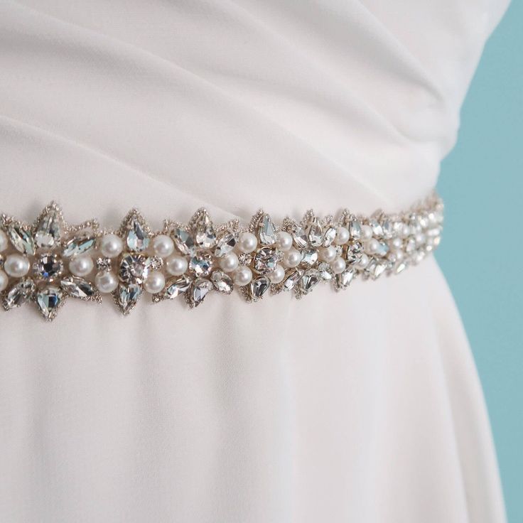 This is a stunning skinny wedding sash belt. This motif on this bridal sash can go well with almost any type of wedding dress. The Swarovski crystals and pearls are disposed in a star like shape and outlining the whole trim is antiqued silver whipstitched thread. The jeweled trim is .86" wide and 24 inches long and it is attached to a silk gazaar ribbon that is  2/3rds of an inch wide. The silk ribbon is bridal white (sometimes called diamond white). It is semi transparent and is also finished w Elegant Bedazzled Bridal Belt For Wedding, Elegant Bedazzled Wedding Sash, Elegant Crystal Bridal Belt, Elegant Crystal Wedding Sashes, Bedazzled White Bridal Belt For Wedding, Elegant Rhinestone Bridal Belt For Bridesmaids, Elegant Silver Bridal Belt For Prom, Elegant Beaded Sashes For Wedding, Elegant Beaded Wedding Sashes