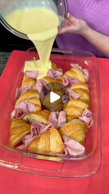 a person pouring sauce on top of pastries in a glass dish with red tray