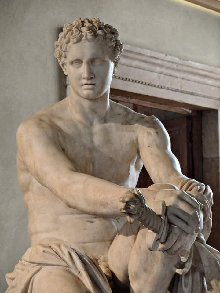 a statue of a man sitting on top of a white marble bench next to a doorway