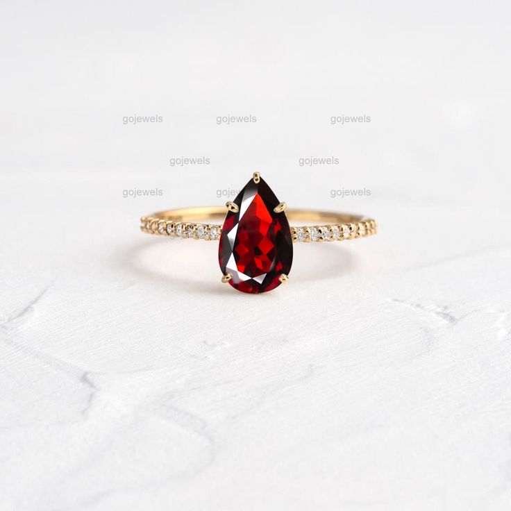 a close up of a ring with a red stone on it's side and diamonds around the band