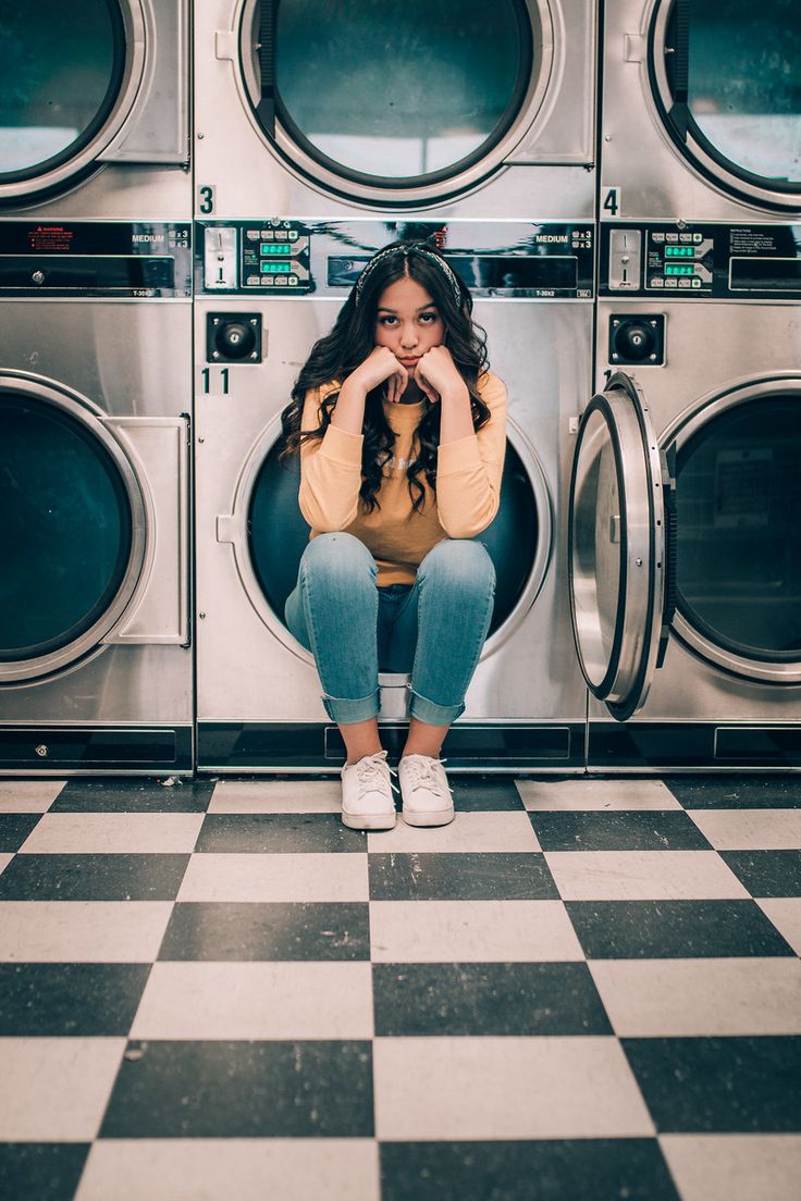 a woman sitting on the floor in front of washers