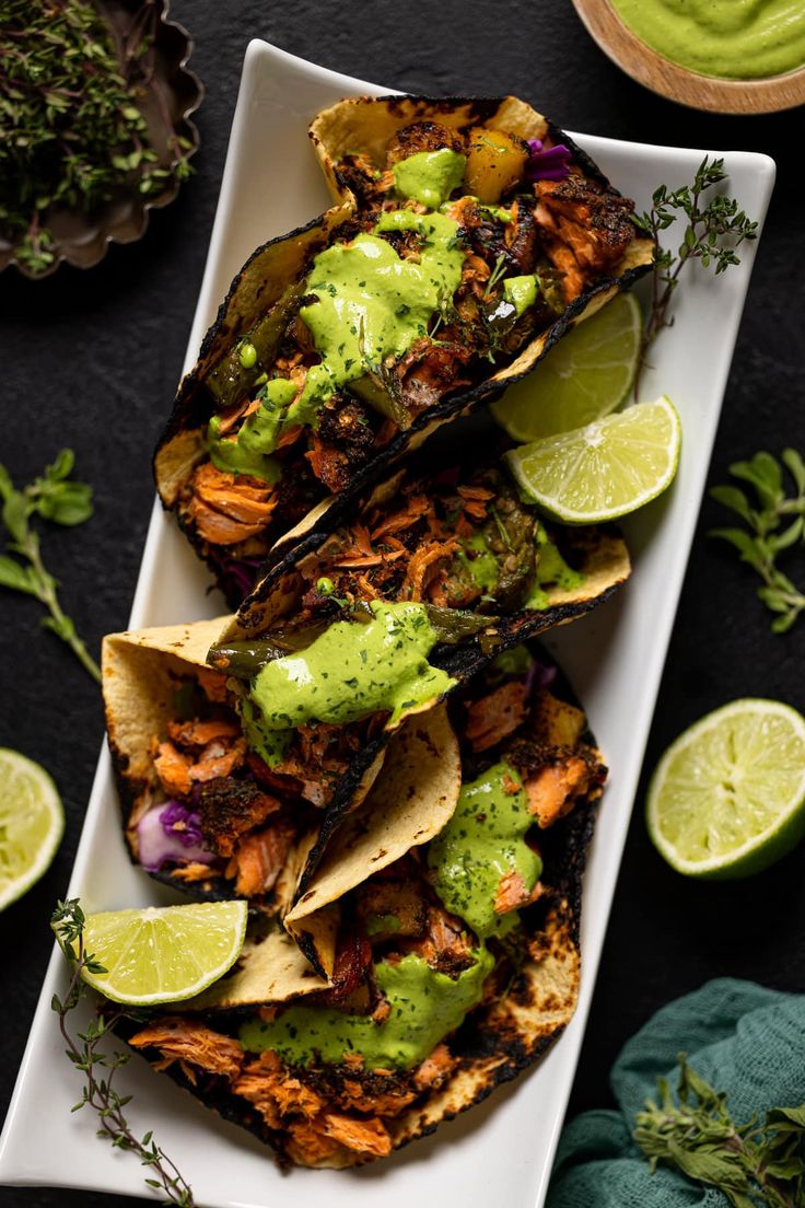 grilled fish tacos with avocado sauce and limes on the side