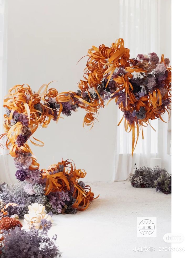 an arrangement of flowers arranged in the shape of a heart on a white floor next to a window