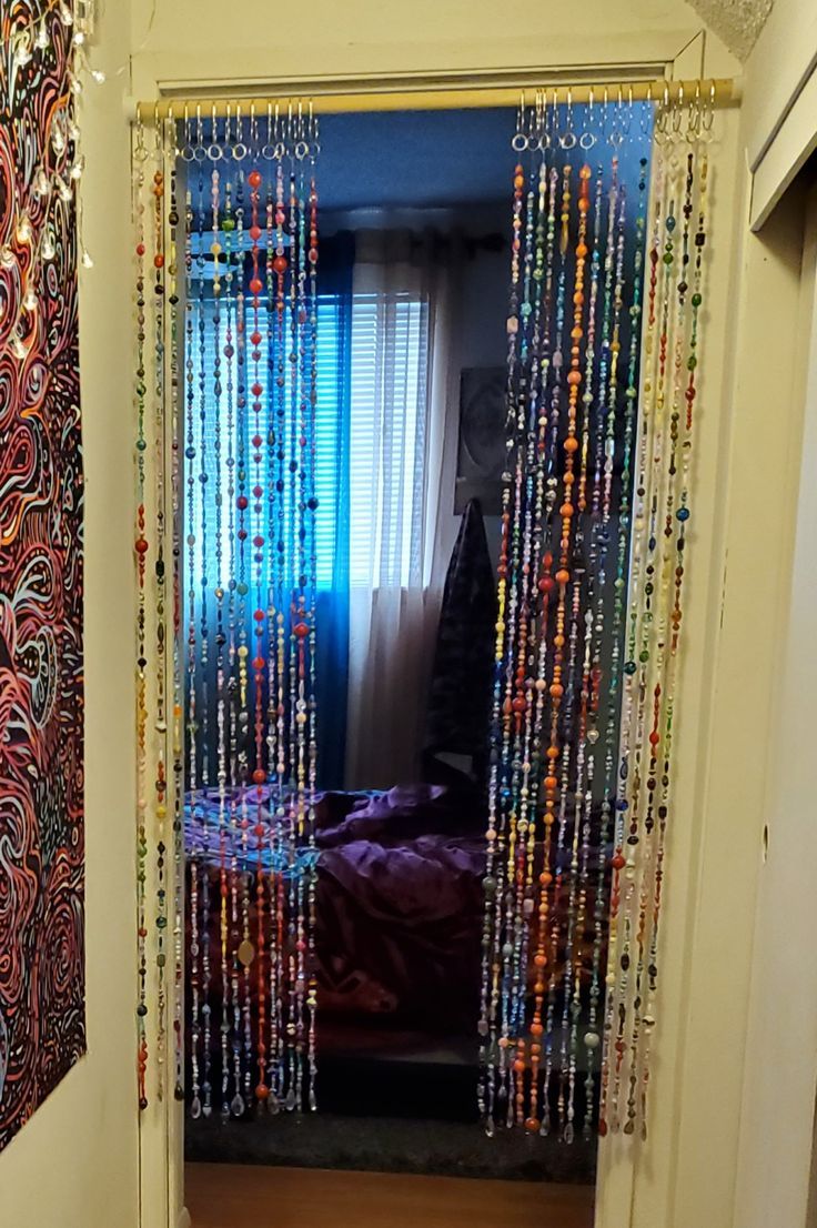 an open door with beaded curtains hanging from it's sides and a bed in the background