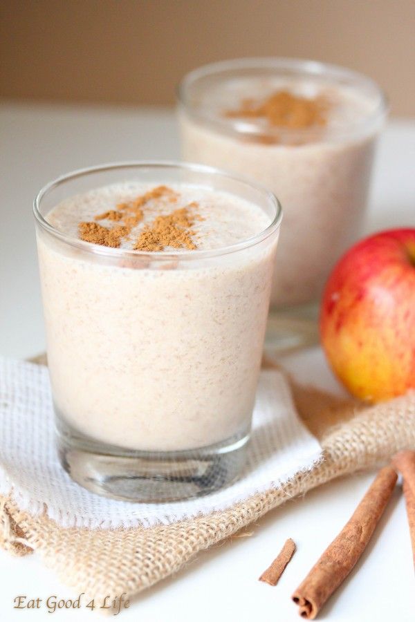 two glasses filled with oatmeal sitting on top of a table next to an apple