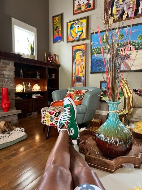 a person's feet resting on the floor in front of a fireplace with pictures above them