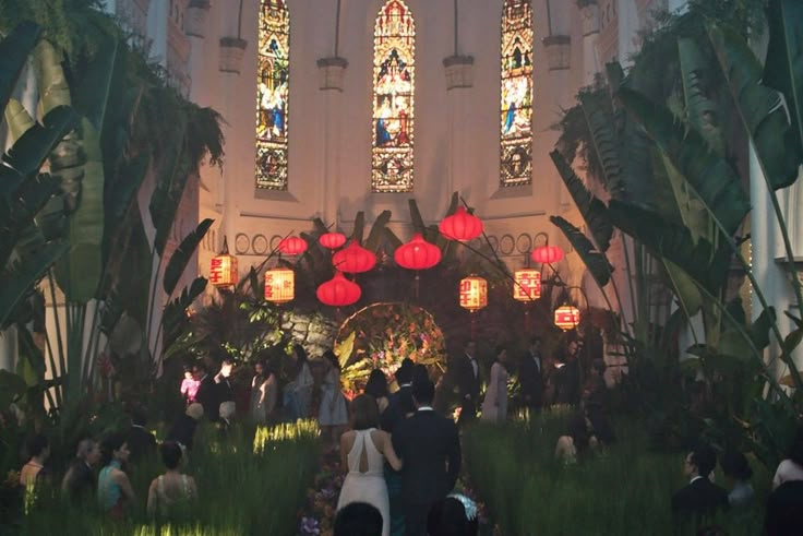 a group of people that are standing in front of some plants and lights at night