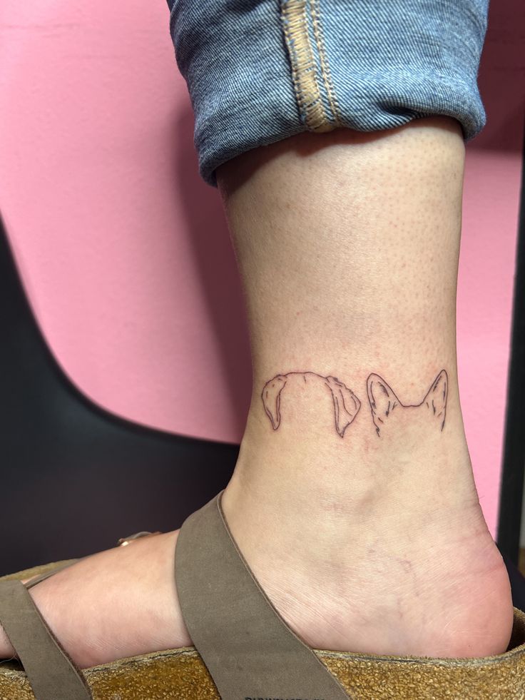 a woman's foot with a small dog tattoo on her left ankle and the word love written in pink ink