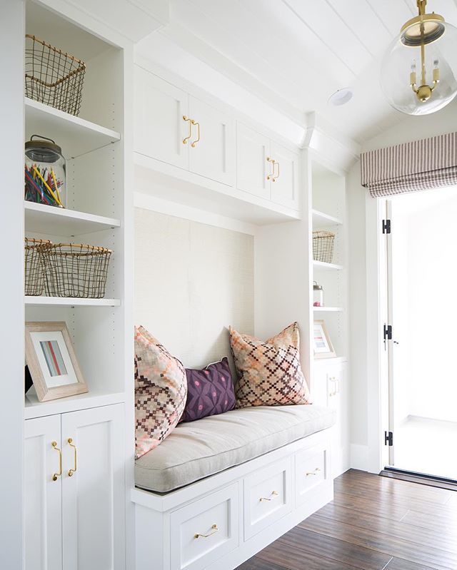 a room with white cabinets and shelves filled with pillows