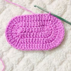 a pink crochet dishcloth with a green knitting needle next to it on a white surface