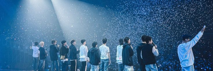 a group of young men standing on top of a stage under rain falling from the sky