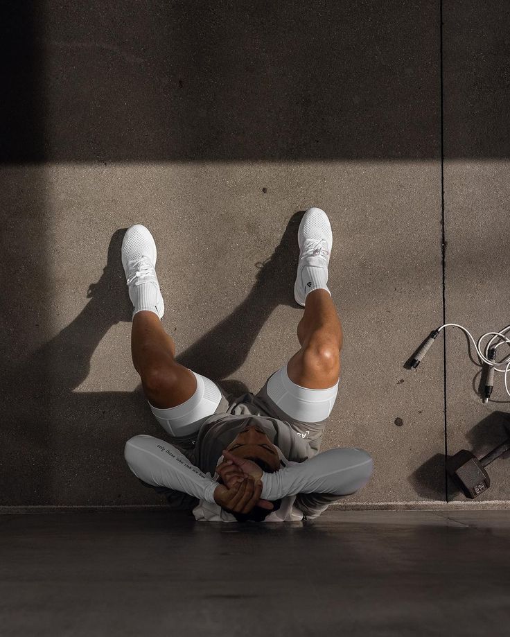 a person laying on the ground with their feet up in front of a wall and wires