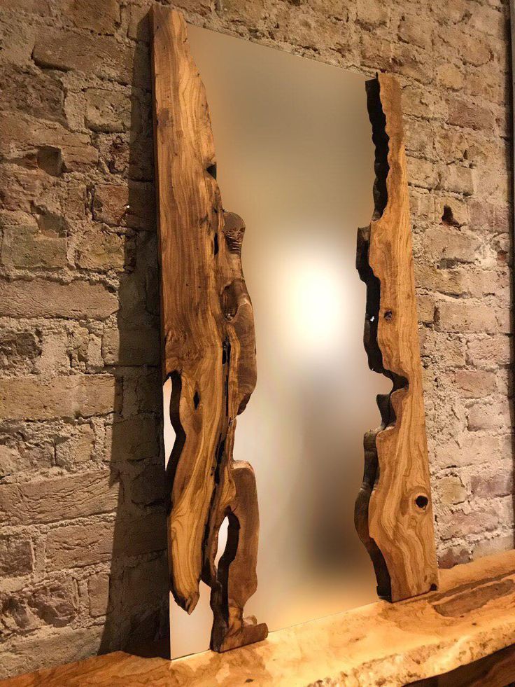 a mirror sitting on top of a wooden shelf next to a brick wall with a reflection in it