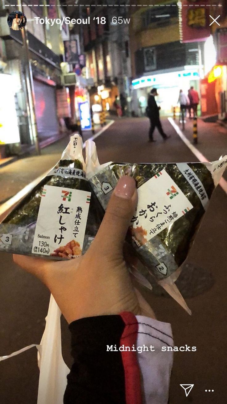 someone holding up some food in their hand on the side of the road at night