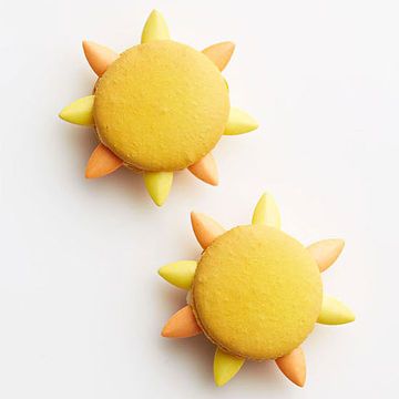 two yellow and orange decorated cookies with spikes on white surface, one is shaped like a sun