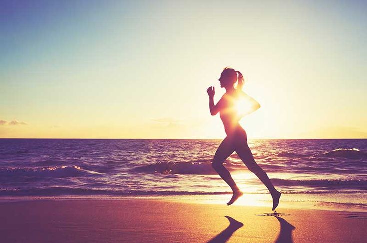 a woman running on the beach at sunset