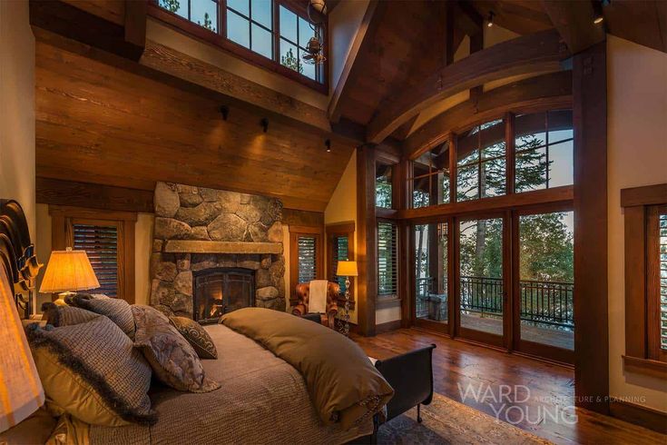 a large bedroom with a stone fireplace in the center and lots of windows on both sides