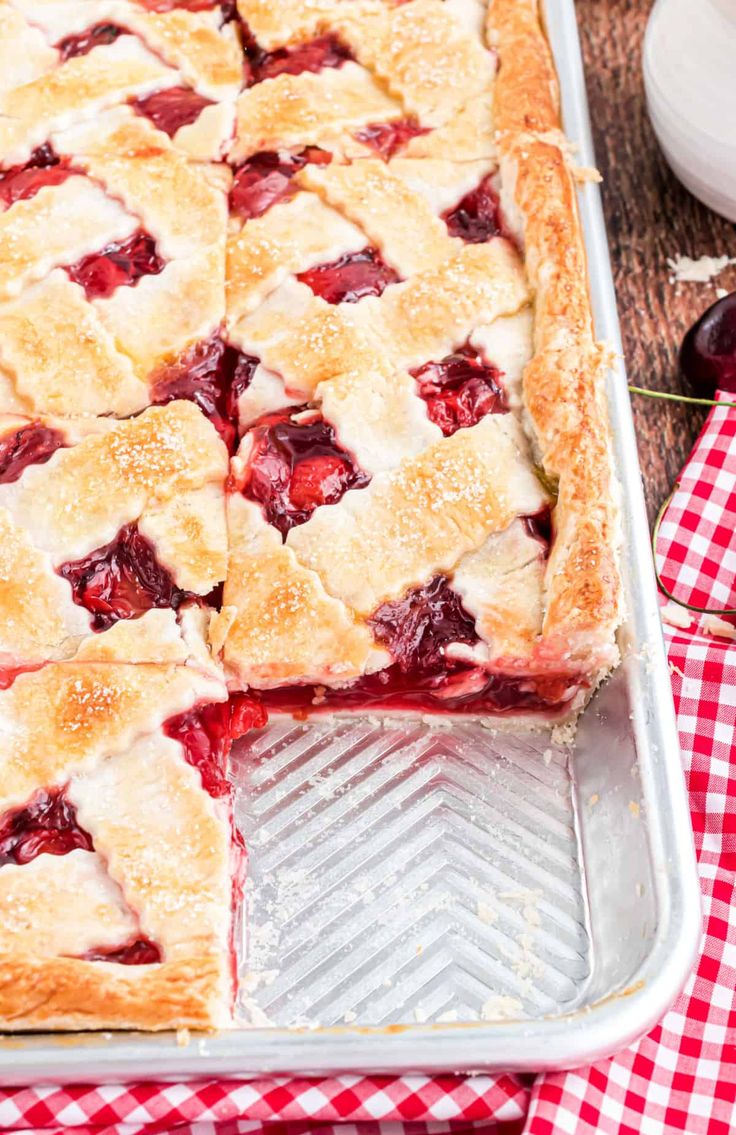 a close up of a pie in a pan with cherries on the table next to it