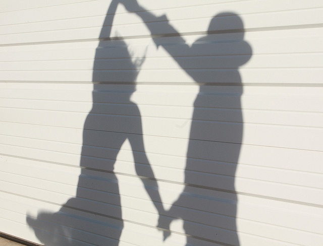 the shadow of two people holding hands in front of a garage door