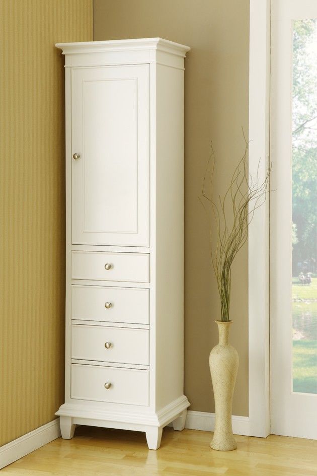 a tall white armoire next to a vase with a plant in it on a hard wood floor