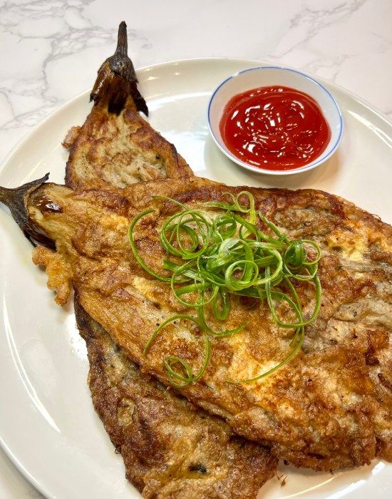 two fried fish on a white plate with ketchup