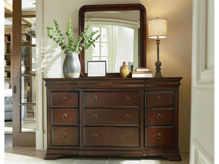 a dresser with a mirror and vase on top