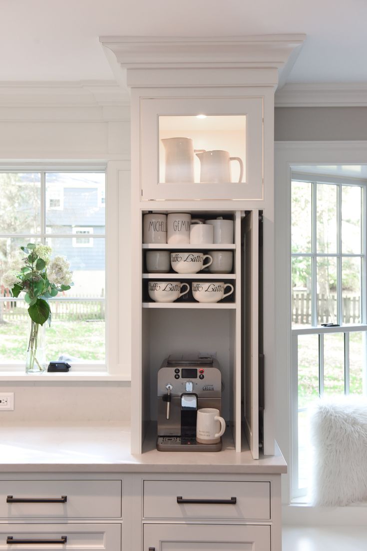 a kitchen with white cabinets and counter tops, coffee maker on the left hand side