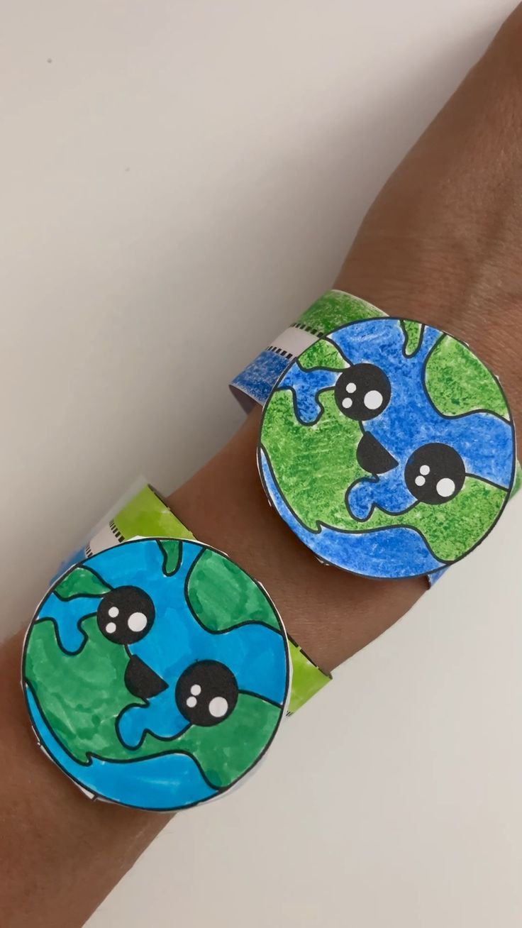 a person's arm with two pieces of paper on it and one piece of the earth covered in googly eyes