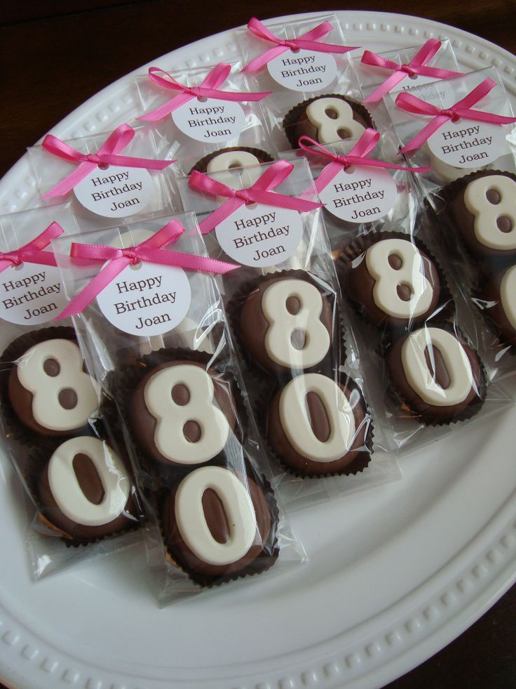 chocolates with white frosting and pink ribbons are arranged on a plate that says happy birthday