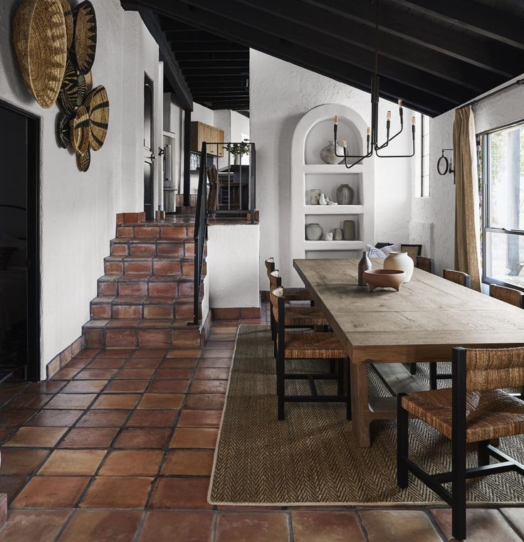 a dining room table and chairs in front of an open doorway with brick steps leading up to the second floor