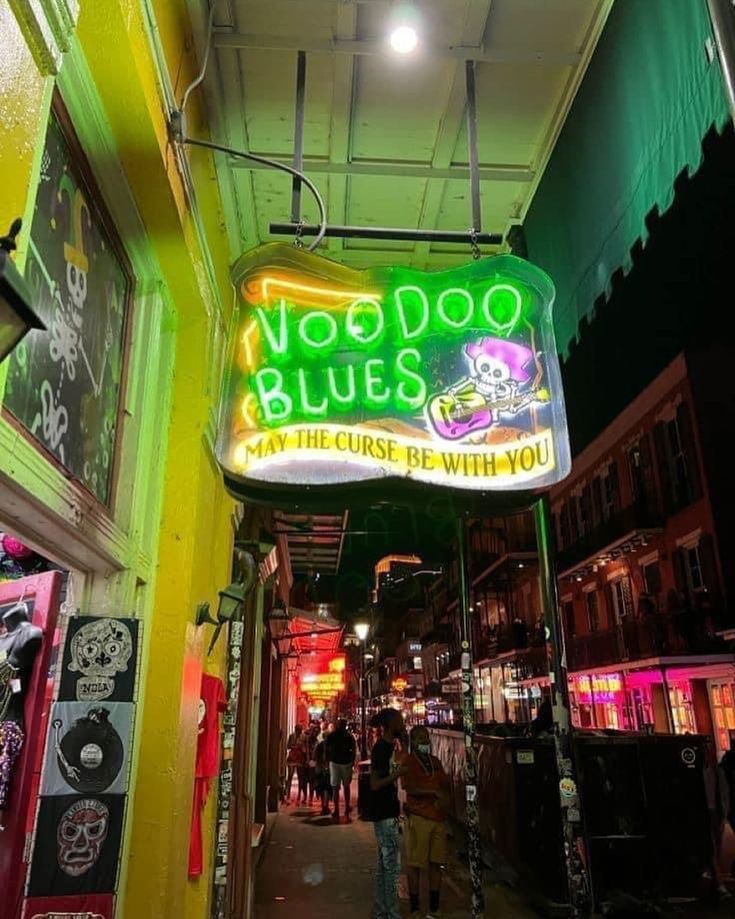 a neon sign that reads voodoo blues on the side of a building in an alleyway