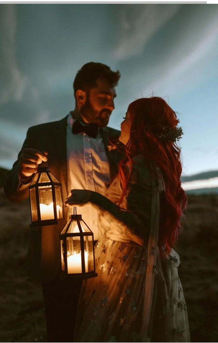 a man and woman standing next to each other holding lanterns