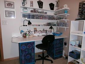 a desk with lots of items on it in a room filled with shelves and pictures