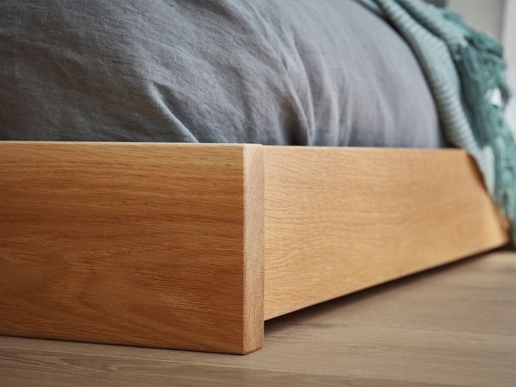 a bed with a wooden head board on it's side and a blue blanket