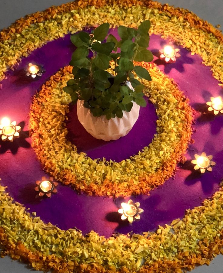 there is a potted plant in the middle of a flowered table with candles on it