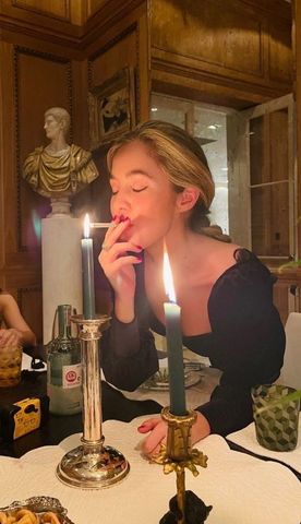 a woman sitting at a table with a candle in front of her and other food on the table