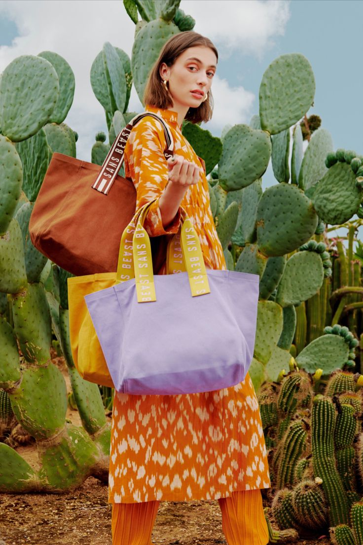 Juliette wears loose pants + dress in orange tones, and carries three Sans Beast canvas tote bags in brown, yellow and light purple. Bags Fashion Photography, Beach Bag Photoshoot, Shopping Bag Photography, Tote Bag Product Photography, Outdoor Bag Photography, Tote Bag Photography Ideas, Tote Bag Photoshoot, Tote Bag Photography, Festival Tote Bag