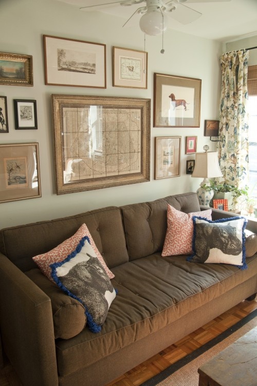 a living room filled with furniture and framed pictures on the wall above it's windows