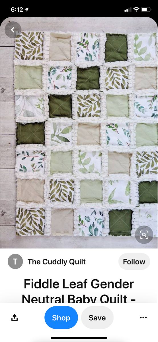 a green and white quilted wall hanging on the side of a wooden floor with leaves