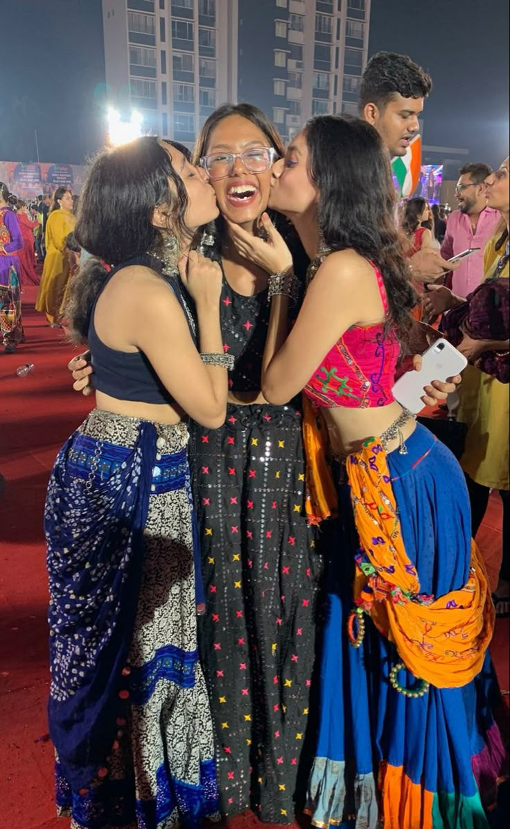 three women are kissing each other while standing in front of a group of people at an event