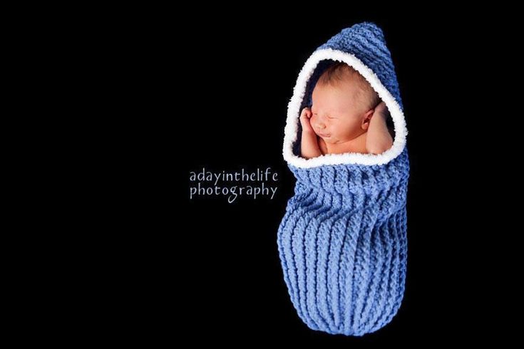 a baby wrapped in a blue and white blanket is laying on top of a black background