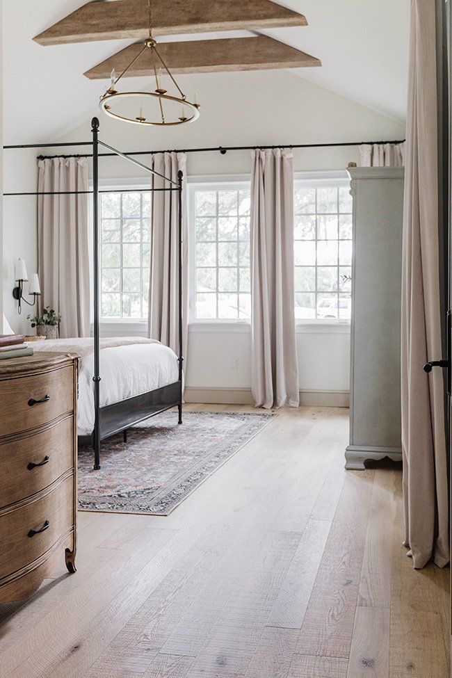 a bedroom with a canopy bed, dresser and window in the corner on the far side