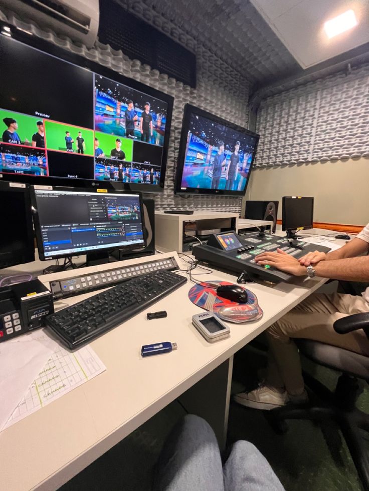 a man sitting at a desk in front of multiple monitors