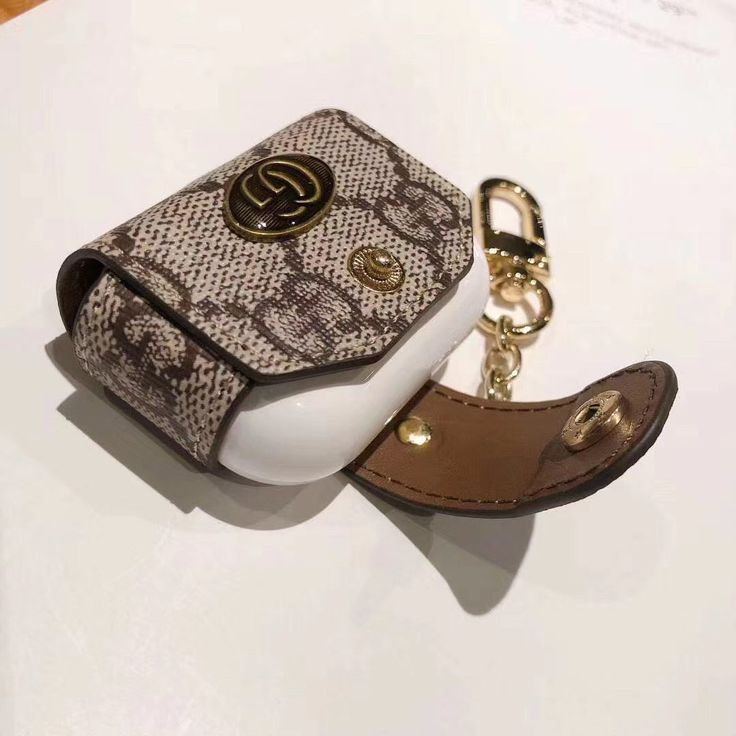 a white and brown snake skin case with a keychain attached to the strap