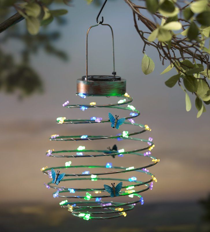 a wind chime hanging from a tree filled with lights