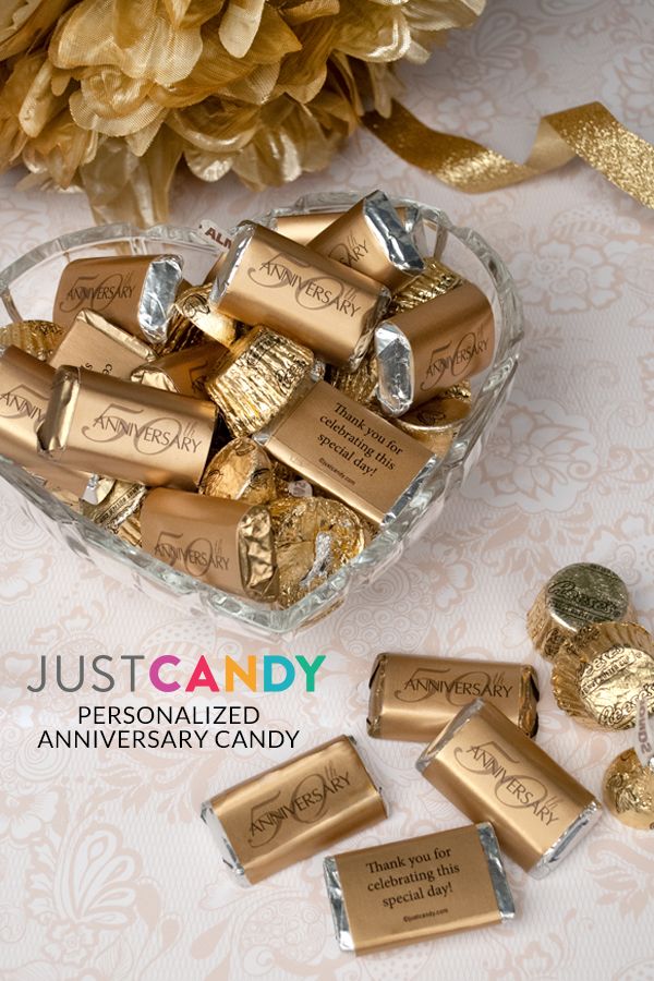 gold foiled candy candies in a heart shaped glass bowl on a table with flowers