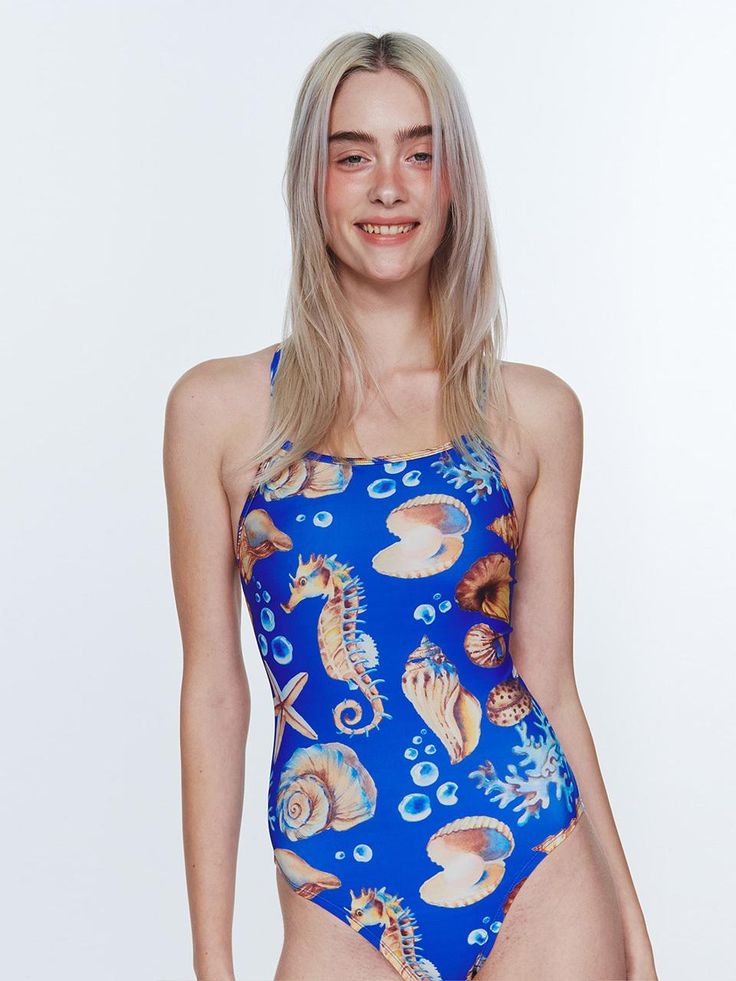 a woman in a blue one piece swimsuit with seahorses and seashells on it